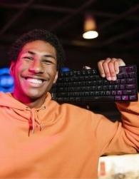 一个高中生把电脑键盘扛在肩上，面带微笑